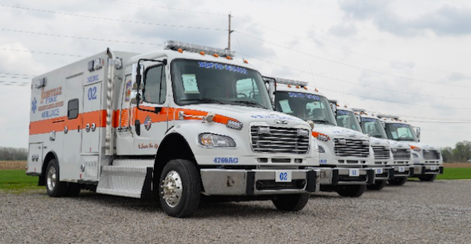 several ambulances lined up on a paved tarmac
