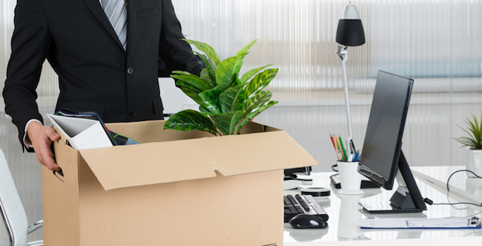 man carrying box full of desk items away from desk