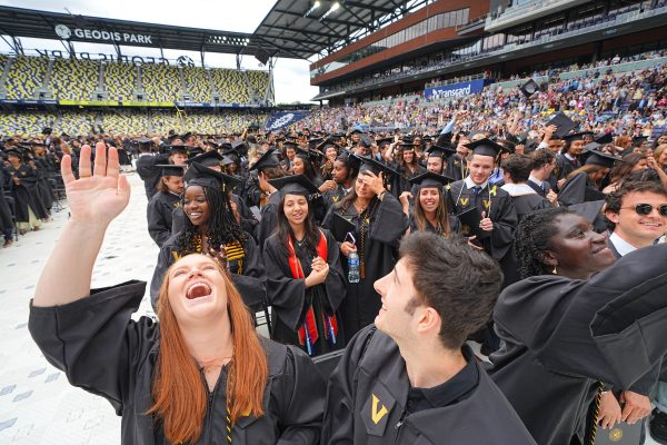 crowd of students wearing black gowns in a stadium