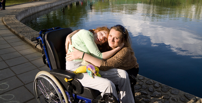 Woman hugging a girl in a wheelchair