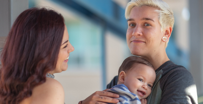 Caucasian couple with woman and nonbinary partner and baby at outdoor market