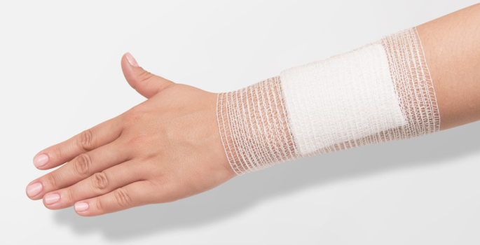 large gauze pad held in place on an arm by an elastic gauze bandage