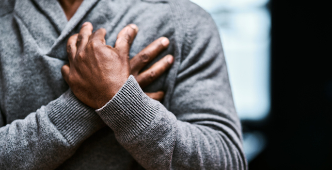 cropped photo of older african american man holding his hands to his chest as if in pain