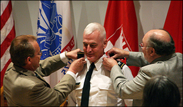 Dean Philippe Fauchet (left) and former Dean Kenneth F. Galloway remove Col. LeBoeuf's shoulder boards and replace them with the brigadier general's one-star shoulder boards.