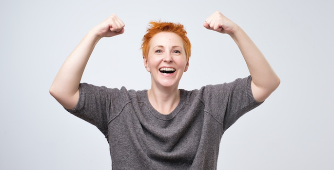 Cheerful mature woman with red short hair smiling with raised fists showing her strength and positive mood. I am the winner concept (Cheerful mature woman with red short hair smiling with raised fists showing her strength and positive mood. I am the w