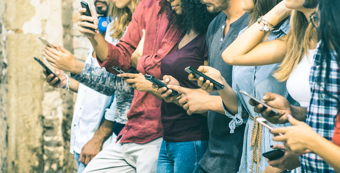 Group of multicultural friends using smartphone outdoors