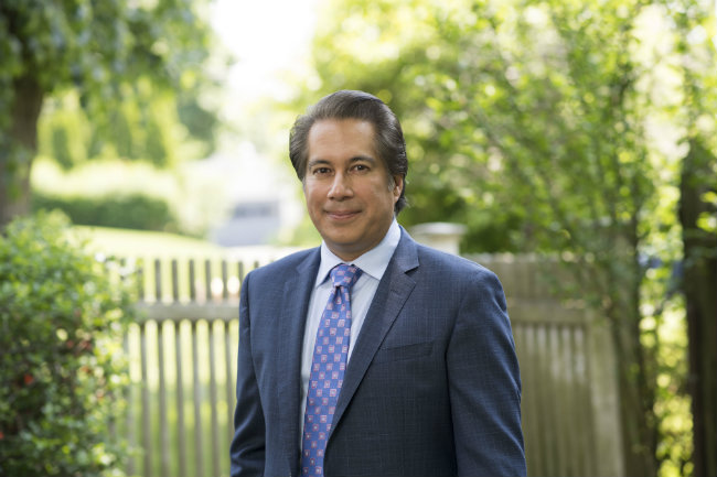 horizontal photo of Blair School Dean Frank Candelaria in front of picket fence