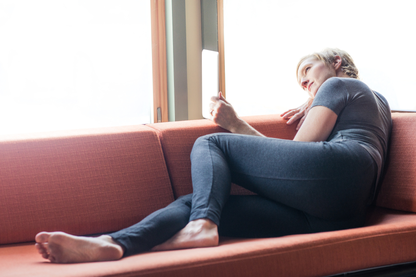 woman reclining on sofa, looking out window