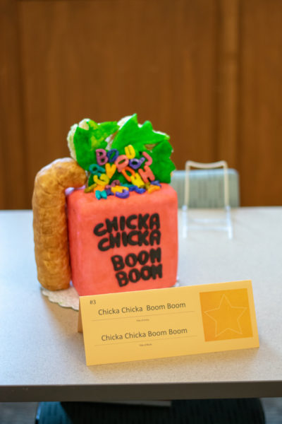 A cake baked to look like a worm crawling up the side of the book to eat a piece of lettuce filled with letters.