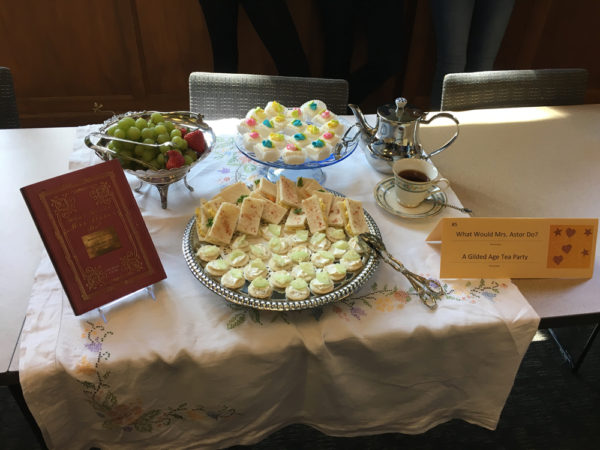 Finger cakes, petite fours, and a tea set laid out on the table.