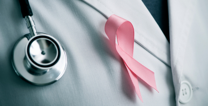 closeup of white doctor's coat with stethoscope and pink breast cancer awareness ribbon