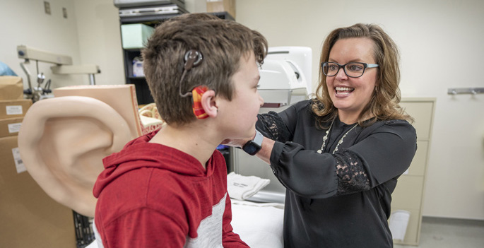 doctor adjusting child's cochlear implant with her hand