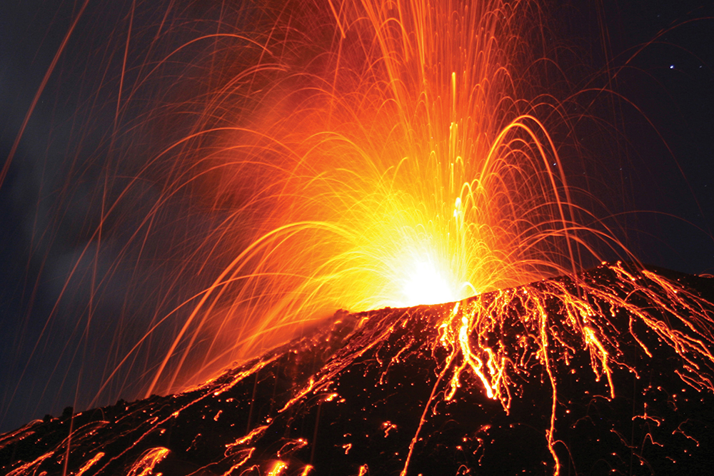 photo of a volcano erupting at night