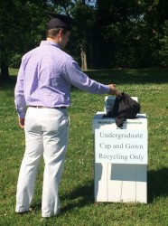 A 2016 graduate drops his recyclable gown into a collection box after Commencement.