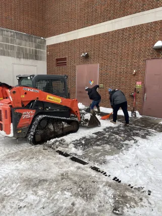 Hall Whitaker operates a rented skid steer alongside Mike Burrs, Matt Holzmer and Henry James III clearing loading docks.
