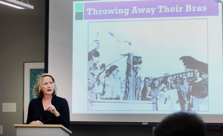 Bonnie Dow in front of powerpoint presentation screen