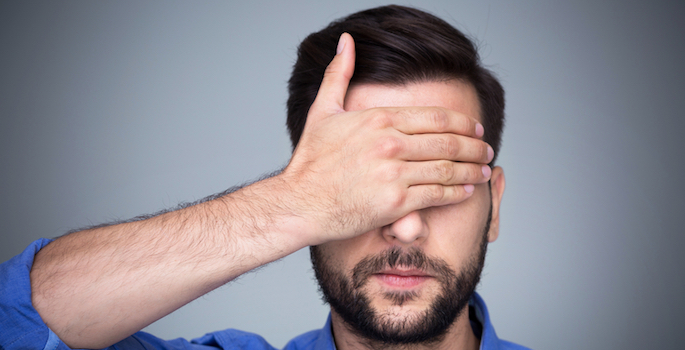 man with hand over his eyes