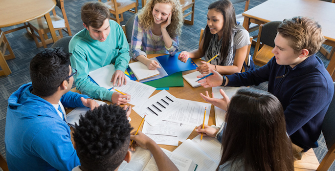 Large diverse group of students studying together in library