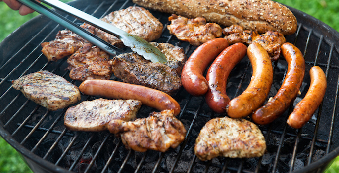 Assorted meat and sausage on grill with the coals, cooking outdoors, weekend concept