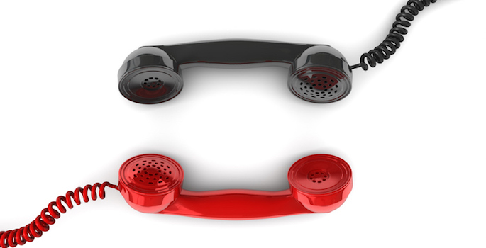 Red telephone handset facing black telephone handset conceptualizing communication between the two