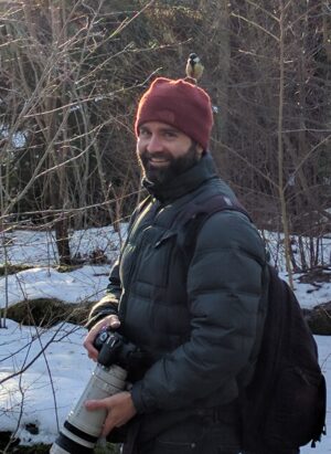 A photo of Matt Wilkins with a bird on his head.