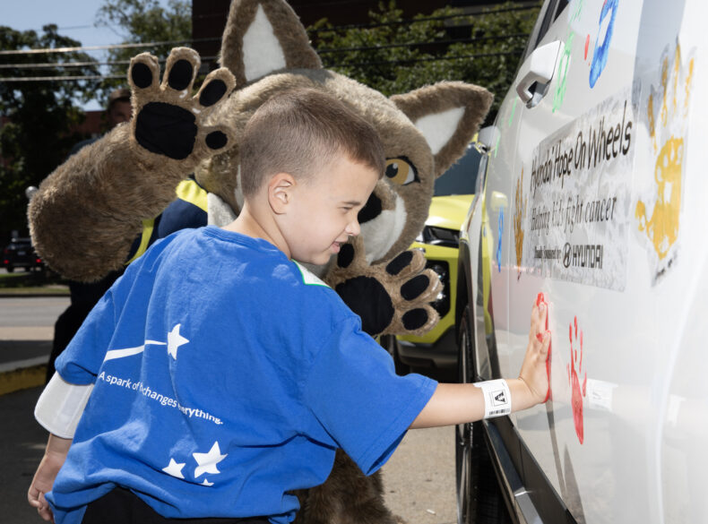 Drake Robideau, 7, puts his handprint on a car with the help of Nashville SC mascot Tempo during the Hyundai Hope on Wheels check presentation and handprint ceremony. (photo by Erin O. Smith)