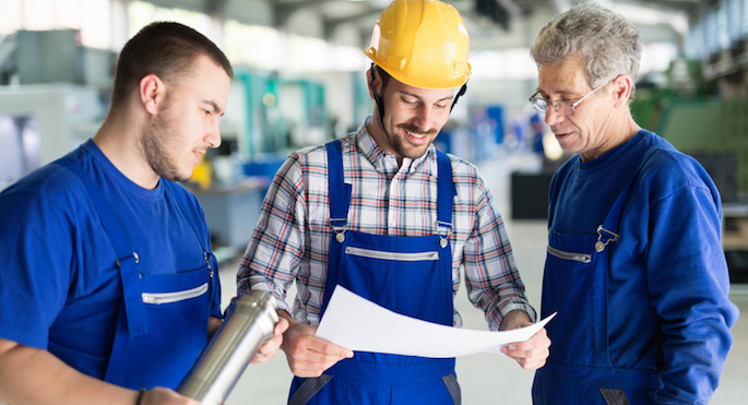factory workers looking at blueprints