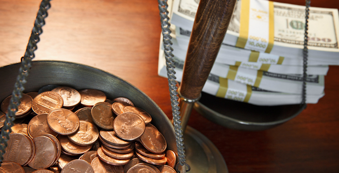 scale showing one tray full of pennies and the other full of stacks of bills