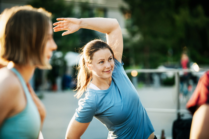 A group of women warming up outside together before going for a run through the city.
