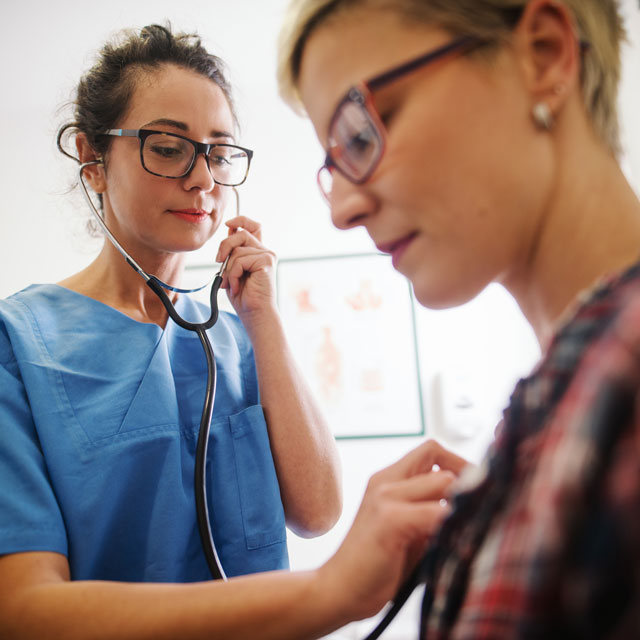 A doctor listens to a patient's heart with a stethoscope.