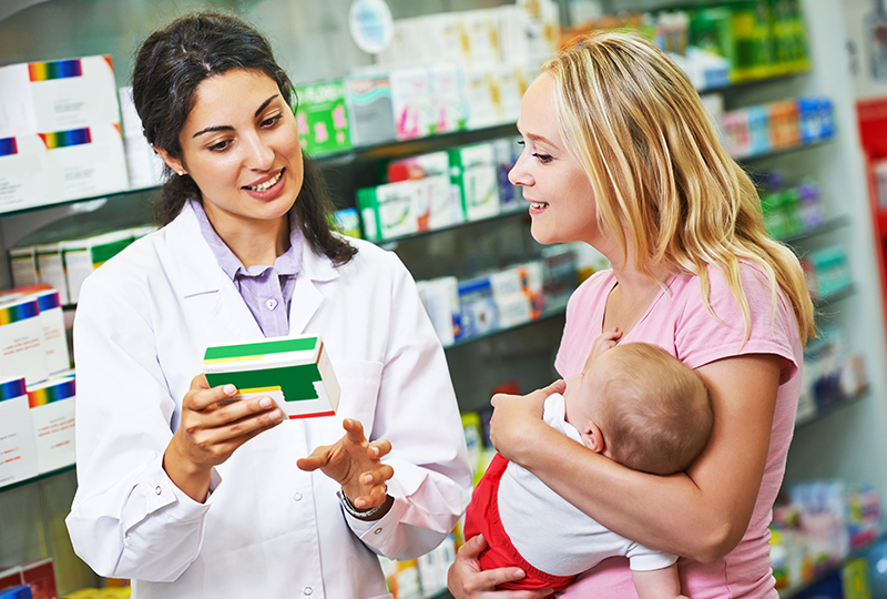 family being helped at pharmacy. Pharmacist explaining antibiotic dosage.