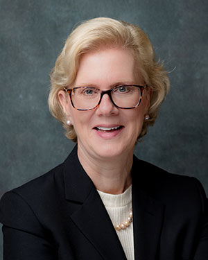 Woman with blonde hair and glasses looking at the camera