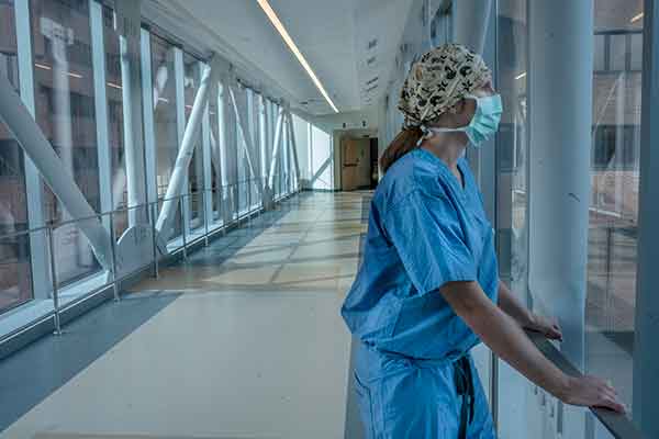 Vanderbilt School of Nursing alumna Lisa Flemmons in scrubs and mask looks out a window on the hospital's sky bridge