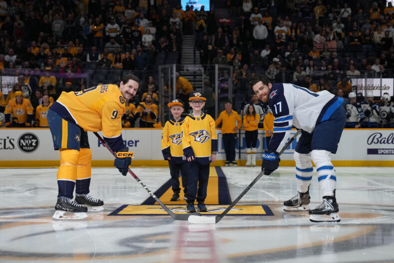 Monroe Carell Jr. Children’s Hospital at Vanderbilt patient Arlo, joined by his twin brother, Luca, took the ice for the Feb. 27 Hockey Fights Cancer game to drop the puck for Predators’ forward Filip Forsberg, left, and Jets’ center Adam Lowry. (photo by John Russell)