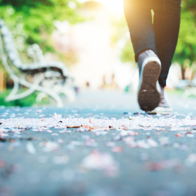 woman's feet in sneakers as she walks a deserted path.