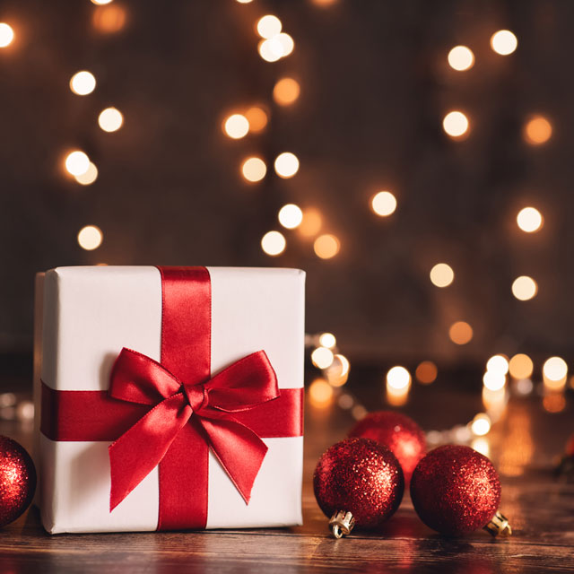 Box gift wrapped in white paper and a big red bow.