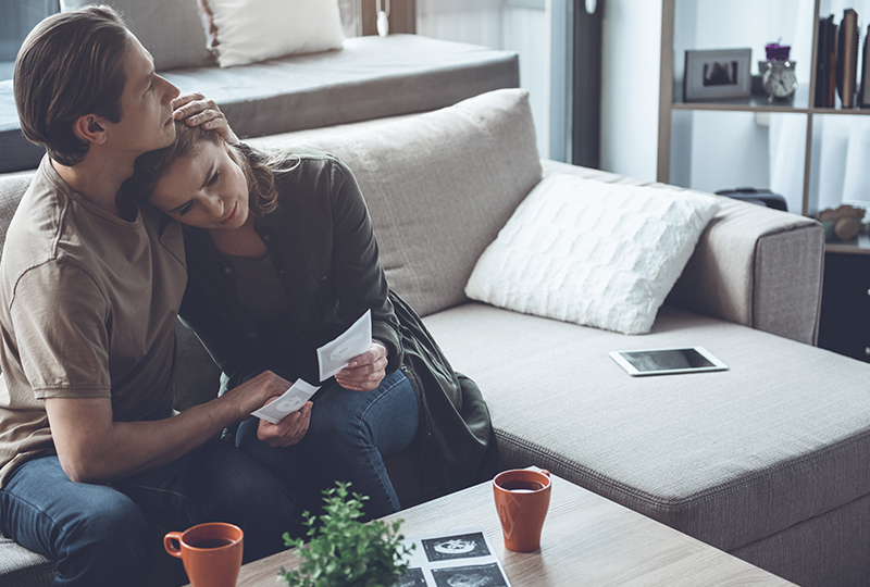 Man comforting woman on couch