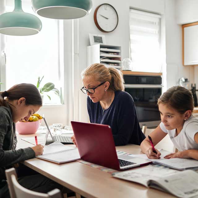 Mother working and children doing schoolwork while maintaining healthy relationship as a family.