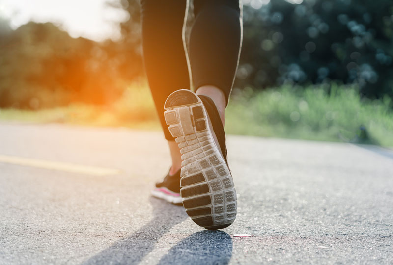 Closeup of a woman's lower legs as she walks on a road