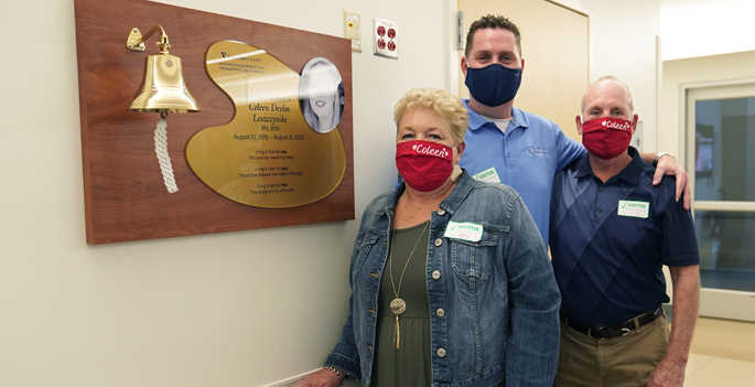 Mark Leszczynski, center, husband of Coleen Leszczynski, along with Coleen’s parents James and Alice Devlin, with the bell dedicated in Coleen’s memory and its accompanying plaque.