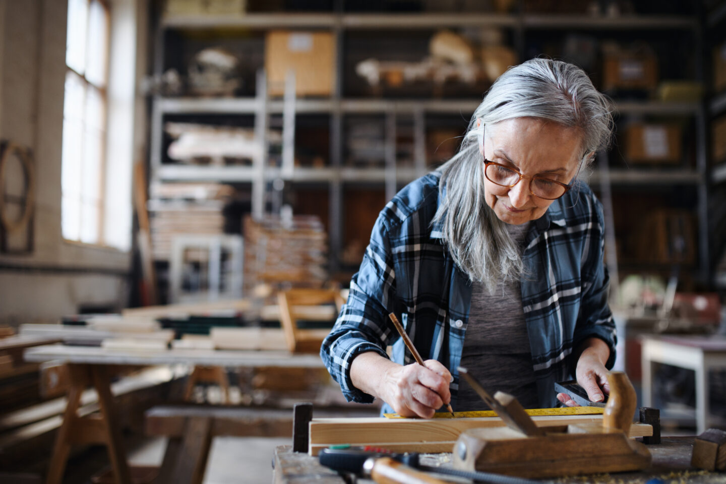 Senior craftswoman working with hand tools in carpentery workshop.