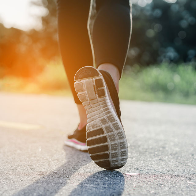 Closeup of a woman's lower legs as she walks on a road