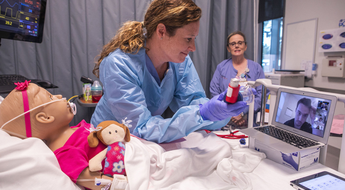 Pediatric instructor Lesley Ann Owen waits for instructions from student Alec Bradbury before providing respiratory care to their pediatric “patient.” Instructor Jennifer Hicks observes and coaches, just as she would in a clinical setting.