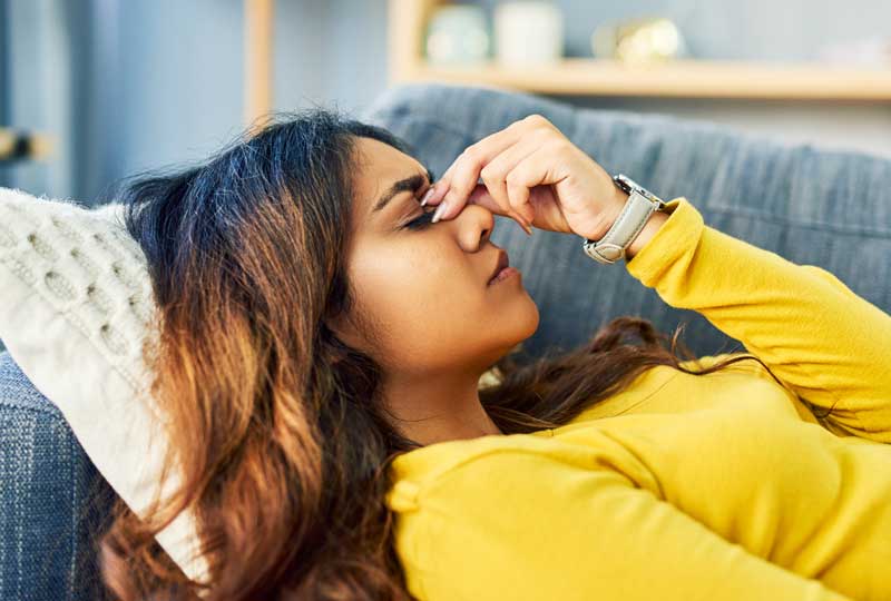 Woman laying on couch trying to treat a tension headache.