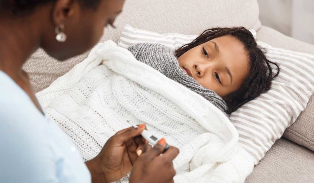 Adolescent laying in bed with a fever as a result of PMIS and Kawasaki Disease.