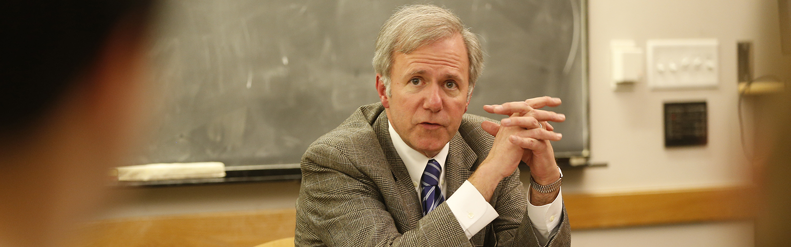 Professor Bill Purcell seated at table as he speaks to his public policy studies class