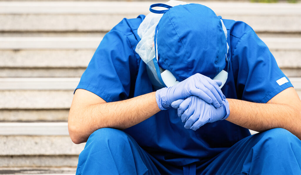 Physician sitting down with head in hands