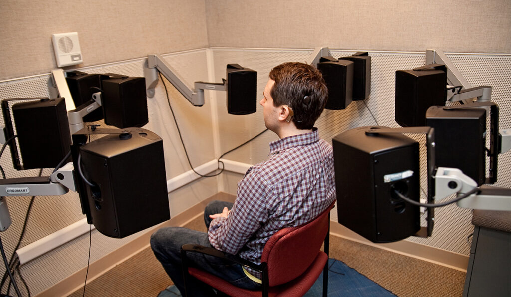 Guy sitting in circle of speakers