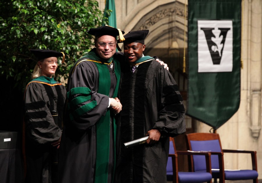 Jeff Balser, M.D., Ph.D., congratulates Owoicho Adogwa at the School of Medicine ceremony in Langford Auditorium. (photo by Anne Rayner)