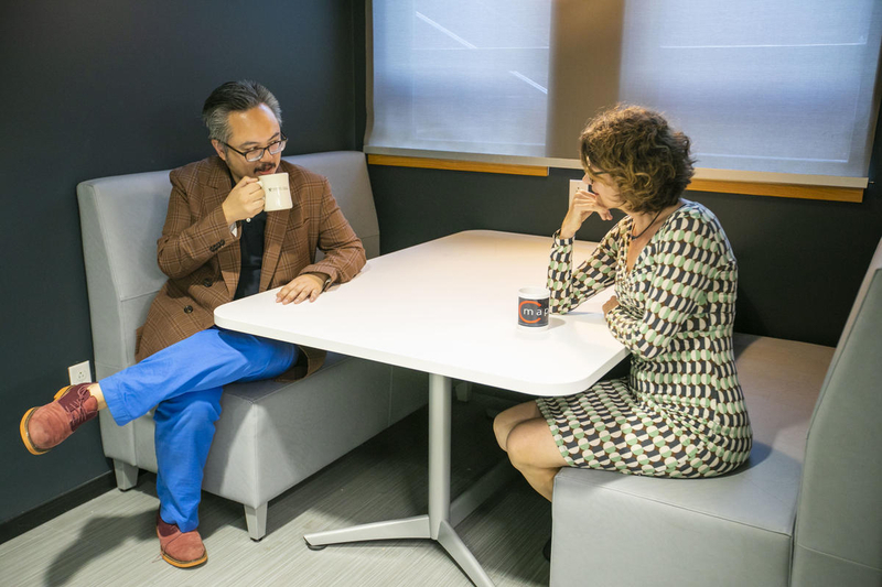 Two faculty members talking and having coffee at a table in the department lounge area